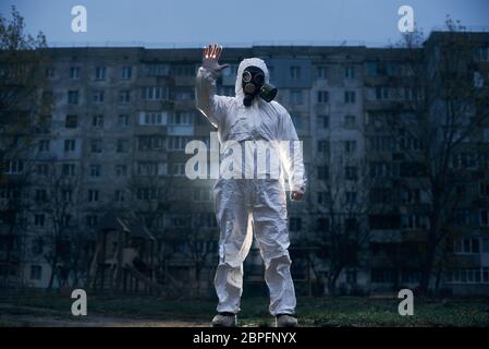 Immagine centrata di un uomo, in piedi davanti ad un alto blocco di appartamenti, che mostra stop sign, vista ad angolo basso, concetto di inquinamento ambientale Foto Stock