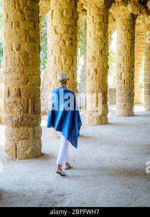 La donna a piedi attraverso un colonnato nel Parco Guell di Barcellona Foto Stock