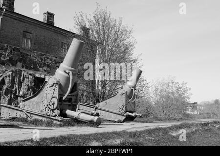 Due cannoni arrugginiti di fronte ad un edificio militare sull'isola Suomenlinna, Finlandia. Un totale di 100 piedi sul mare rocca - elaborazione monocromatica Foto Stock