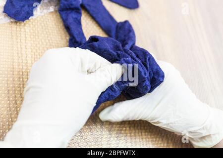 Workshop di mano facendo un vello guanti blu da lana di pecora Merino utilizzando umido processo di infeltrimento - artigiano controlla il vello del guanto feltrato Foto Stock