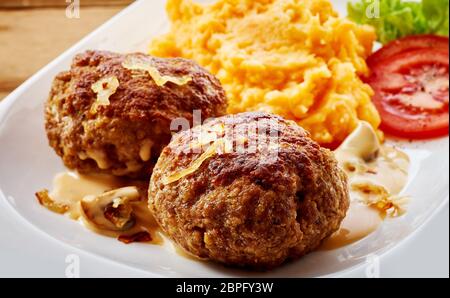 Il tedesco le polpette di carne o frikadellen in stretta fino servita con cipolla fritti e una miscela di purè di carote e patate Foto Stock