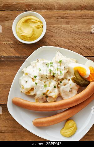 Il tedesco bockwurst salsiccia con insalata di patate, uovo sodo e senape in una vista aerea Foto Stock