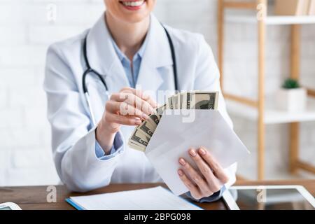 Medicina costosa. Il medico sorridente conta i soldi nella busta Foto Stock