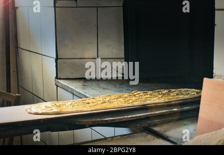 Pane tradizionale ramadan di cucina turca su pala da forno che viene messo nel forno al più santo di mesi di musulmani Foto Stock