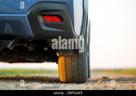 Primo piano della ruota blu fuoristrada su strada di ghiaia. Viaggiando in auto, avventura nella fauna selvatica, spedizione o viaggio estremo su un SUV auto. Offroa Foto Stock