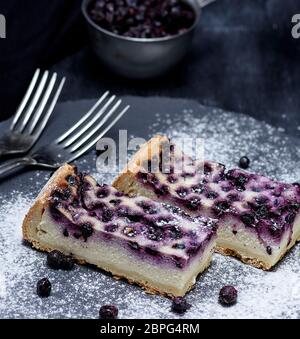 Pezzi di torta di ricotta e mirtilli su sfondo nero Foto Stock