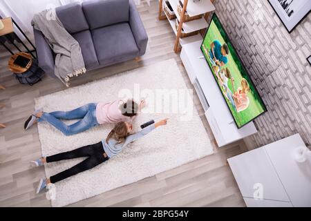 Madre e figlia giacente su un tappeto o guardare la televisione a casa Foto Stock