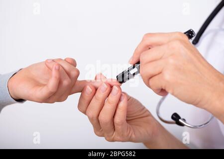 Close-up di un medico mano la misurazione del sangue del paziente a livello di zucchero con il glucometro Foto Stock