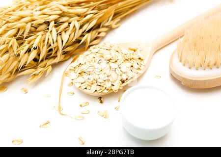 Pelle naturale prodotto di pulitura per body detox. Fiocchi di avena, panna, latte di avena, scrub del corpo spazzola, tavolo bianco, home spa. Foto Stock