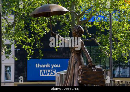 Una statua del personaggio del film Mary Poppins in Leicester Square di Londra vista di fronte al tabellone del cinema Odeon ringraziando i lavoratori NHS. La piazza i Foto Stock