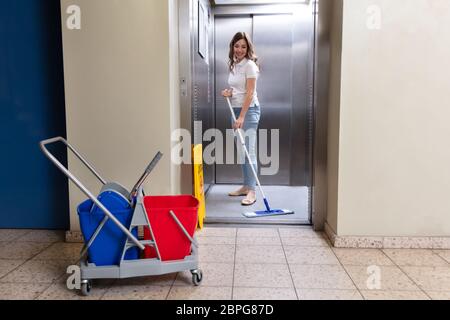 Felice femmina pulizia bidello di ascensore con Mop Foto Stock