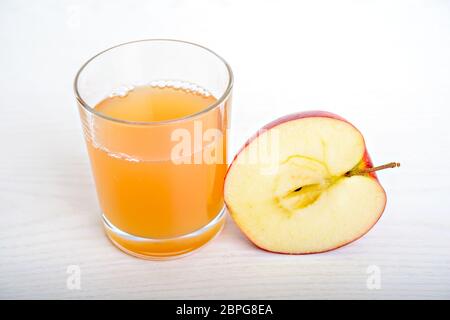 Mezza mela con vetro di naturalmente succo torbido di fronte a uno sfondo bianco Foto Stock