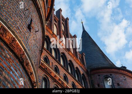 Vista frontale di Holstentor a Lübeck verso il cielo, patrimonio dell'umanità dell'UNESCO, simbolo gotico storico paesaggio urbano ornamenti restaurati in mattoni Foto Stock
