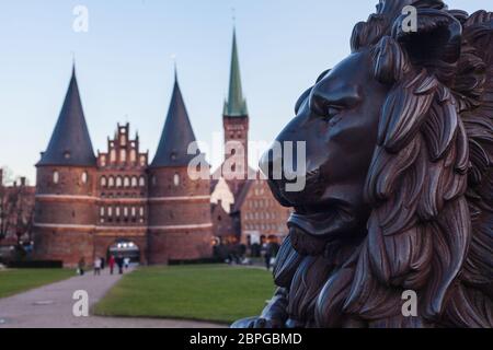 Holstentor a Lübeck con la statua del leone in primo piano, patrimonio dell'umanità dell'UNESCO, simbolo di stile gotico, ornamenti storici del paesaggio urbano restaurato in mattoni P. Foto Stock