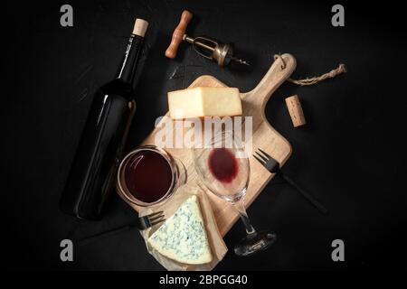 Degustazione di vino e formaggi, girato dall'alto su sfondo nero, con cavatappi vintage e una bottiglia Foto Stock
