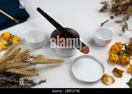 Botanico aromatico cosmetici. Le erbe aromatiche essiccate fiori miscela, fango facciale della maschera di argilla, oli, applicazione a pennello. A base di erbe olistico skincare bellezza hack Foto Stock
