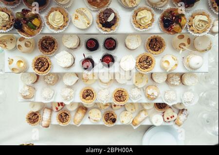 Edicola con dolci, caramelle, dessert, cupcake, muffin, torte, eclair decorati con fiori Foto Stock