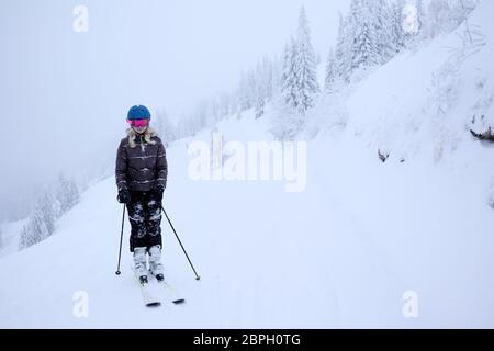 la giovane ragazza sta sciando in un paesaggio invernale innevato Foto Stock