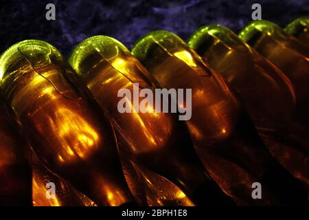 Close up righe retroilluminato di vino bianco bottiglie in vetro impilati l affinamento in cantina Foto Stock