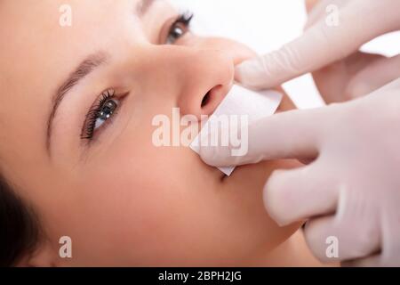 Close-up del terapeuta di ceratura di mano della donna del labbro superiore nella Spa Foto Stock