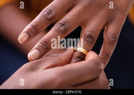 Close-up di mano d'uomo mettendo Golden anello di fidanzamento sulla donna del dito Foto Stock