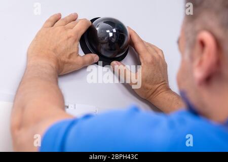 Close-up del maschio a mano per il tecnico Installa videocamera di sorveglianza sulla parete Foto Stock