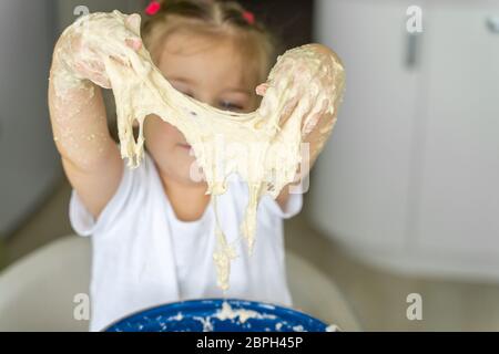 3-4 anni ragazza impastano lievito pasta, concentrarsi sulla mani closeup. tempo libero per la famiglia Foto Stock