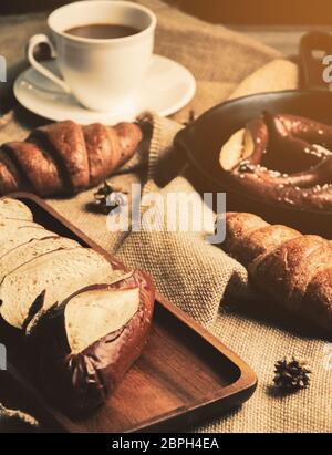 Pane di baguette francese, croissant e pretzel con tazza di caffè su tessuto di sacco. Concetto di colazione Foto Stock