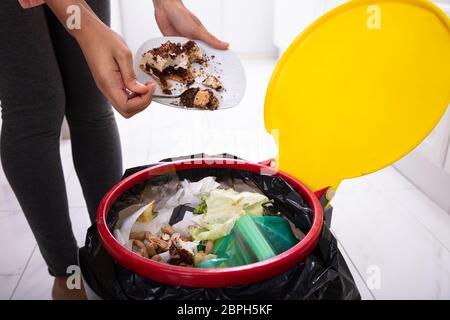 Close-up di una donna di mano Torta di gettare nel cestino Foto Stock