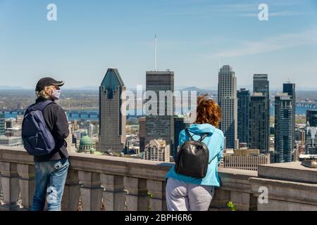 Montreal, CA - 18 Maggio 2020 : uomo che indossa una maschera in mezzo all'esplosione del coronavirus guardando lo skyline di Montreal dalla cima del Monte Royal Foto Stock