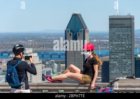 Montreal, CA - 18 Maggio 2020 : giovane donna che indossa la maschera facciale tra l'epidemia di coronavirus che posa per la fotografia di fronte allo skyline di Montreal. Foto Stock