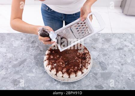 Ritratto di un sorridente giovane donna cioccolato reticolo sulla torta Foto Stock