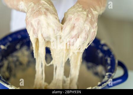 3-4 anni ragazza impasta lievito impasto in una padella blu, mani closeup. tempo libero per la famiglia Foto Stock