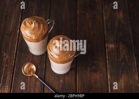 Vista dall'alto di due bicchieri con il famoso caffè Dalgona su un tavolo di legno scuro Foto Stock