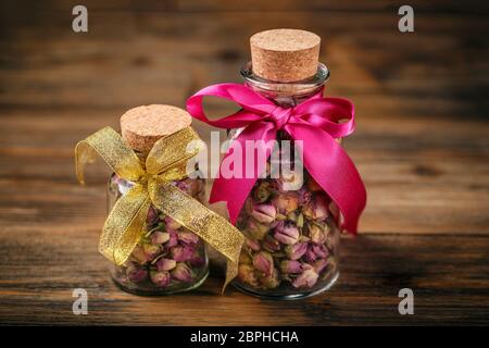 Boccioli di rosa in vasetti di vetro su sfondo di legno Foto Stock