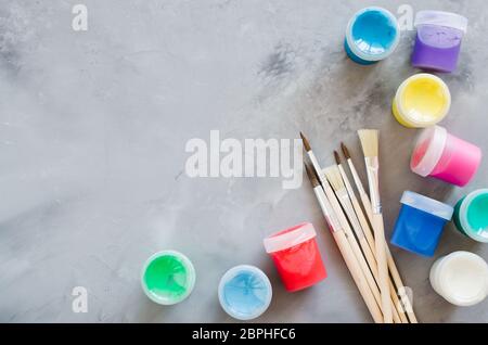 Gli strumenti di disegno, set di pulizia dei pennelli e vernici multicolore su sfondo grigio. Pennelli di diverse dimensioni. Copia spazio, vista dall'alto Foto Stock