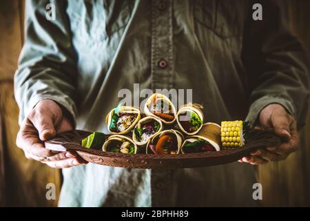 Uomo con spuntini e salse. Tortilla cibo messicano. Cibo per feste. Chef con tapas Foto Stock