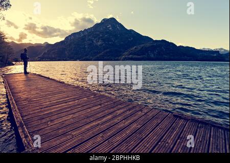 Escursionista in piedi sul dock fine sul lago. Tramper guardando il tramonto sul lago. Foto Stock