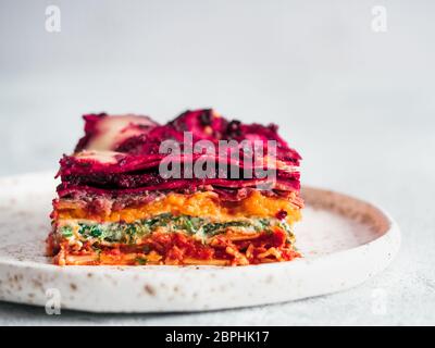 Ortaggio pranzo Rainbow lasagne sulla piastra di artigianato. Idee e ricette per vegetariani sani per pranzo o cena. Lasagne con barbabietola, zucca, funghi, Foto Stock