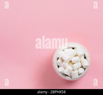 Marshmallows su sfondo rosa con copyspace. Appartamento laici o vista dall'alto. Lo sfondo o la texture di coloratissimi mini marshmallows. Inverno sfondo alimentare conc Foto Stock