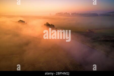 Vista aerea della mattina nebbiosa fiume e campi rurali. Colori d'autunno mattina. Sunrise scena di caduta dall'alto. Regione di Minsk, Bielorussia. Foto Stock