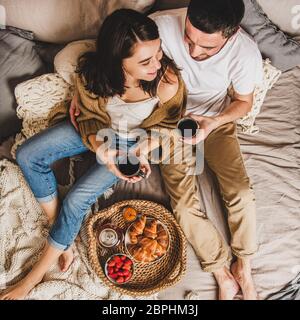 Buona coppia che ha fatto colazione a letto e abbracciare, raccolto quadrato Foto Stock