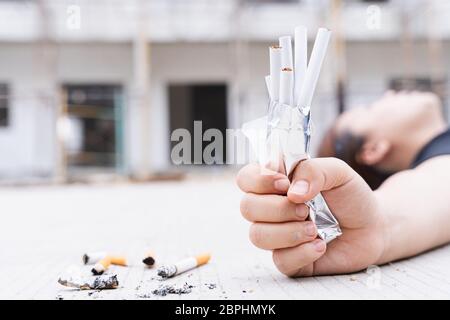 Primo piano la mano della giovane donna schiaccia il pacco di sigarette e si stette sul pavimento. Mondo no tabacco giorno. Foto Stock