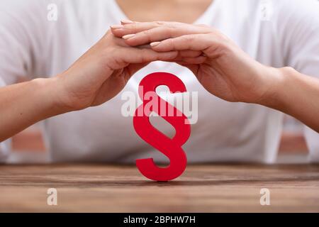 Close-up di donna di mano rosso di protezione del paragrafo sopra la scrivania in legno Foto Stock