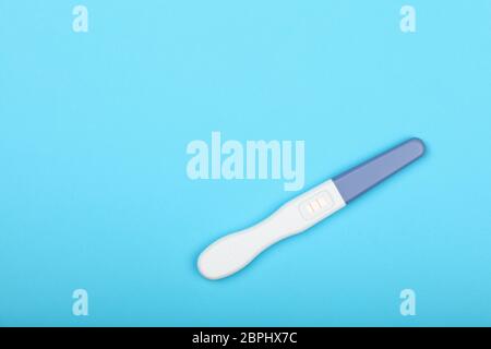 Chiudere uno positivo (gravidanza) Risultato test di gravidanza pastello su carta blu, sfondo elevato angolo di alta vista, direttamente al di sopra di Foto Stock