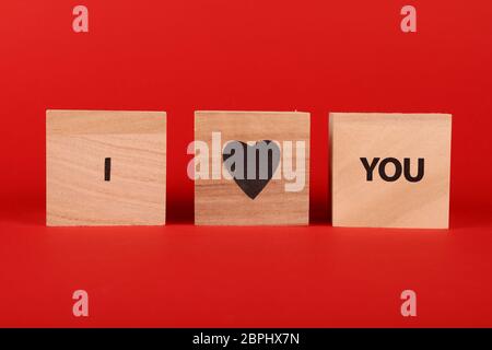 Cubo di legno con segni TI AMO parole su sfondo rosso e spazio copia a basso angolo di visione Foto Stock