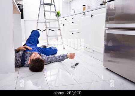 Close-up di inconscio tuttofare sdraiato sul pavimento in cucina Foto Stock