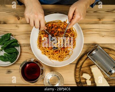 Foto di una piastra di tradizionali spaghetti alla bolognese e bicchiere di vino rosso dal di sopra. Foto Stock