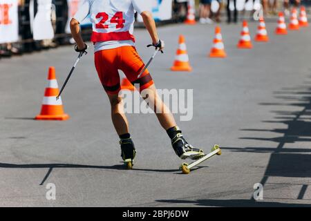 indietro atleta skier pista di sci a rulli su asfalto con cono stradale Foto Stock