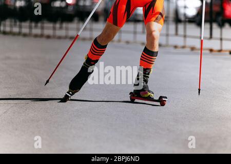 gambe di atleta di sci su roller ski e pali Foto Stock